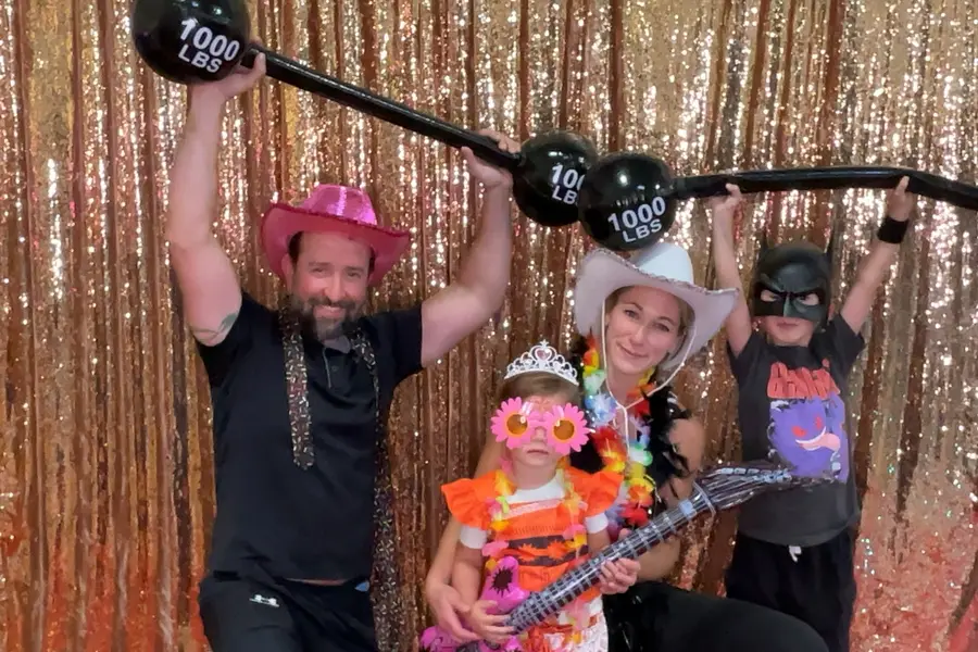 A family posing with playful weightlifting props at a party